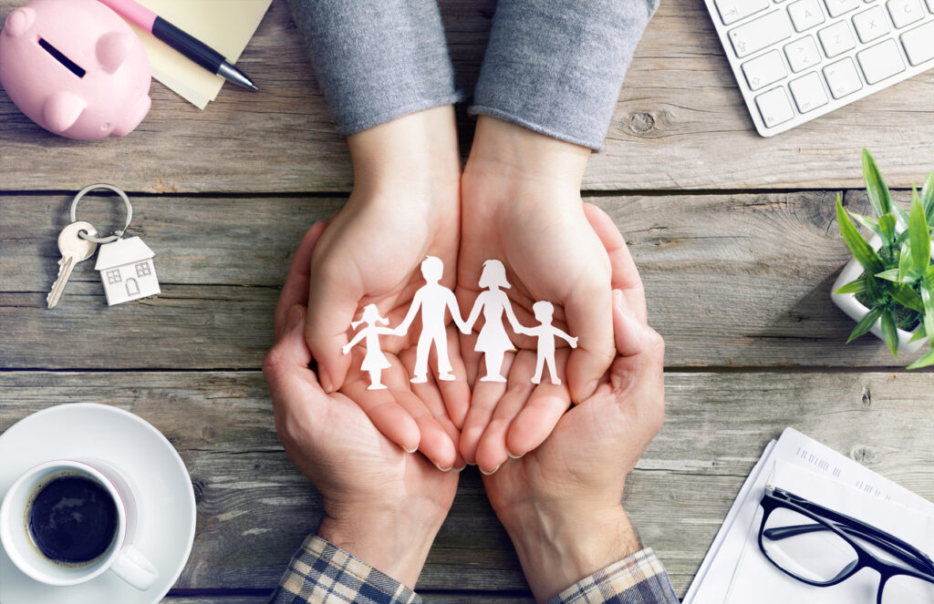 Hands holding paper cutout of a family